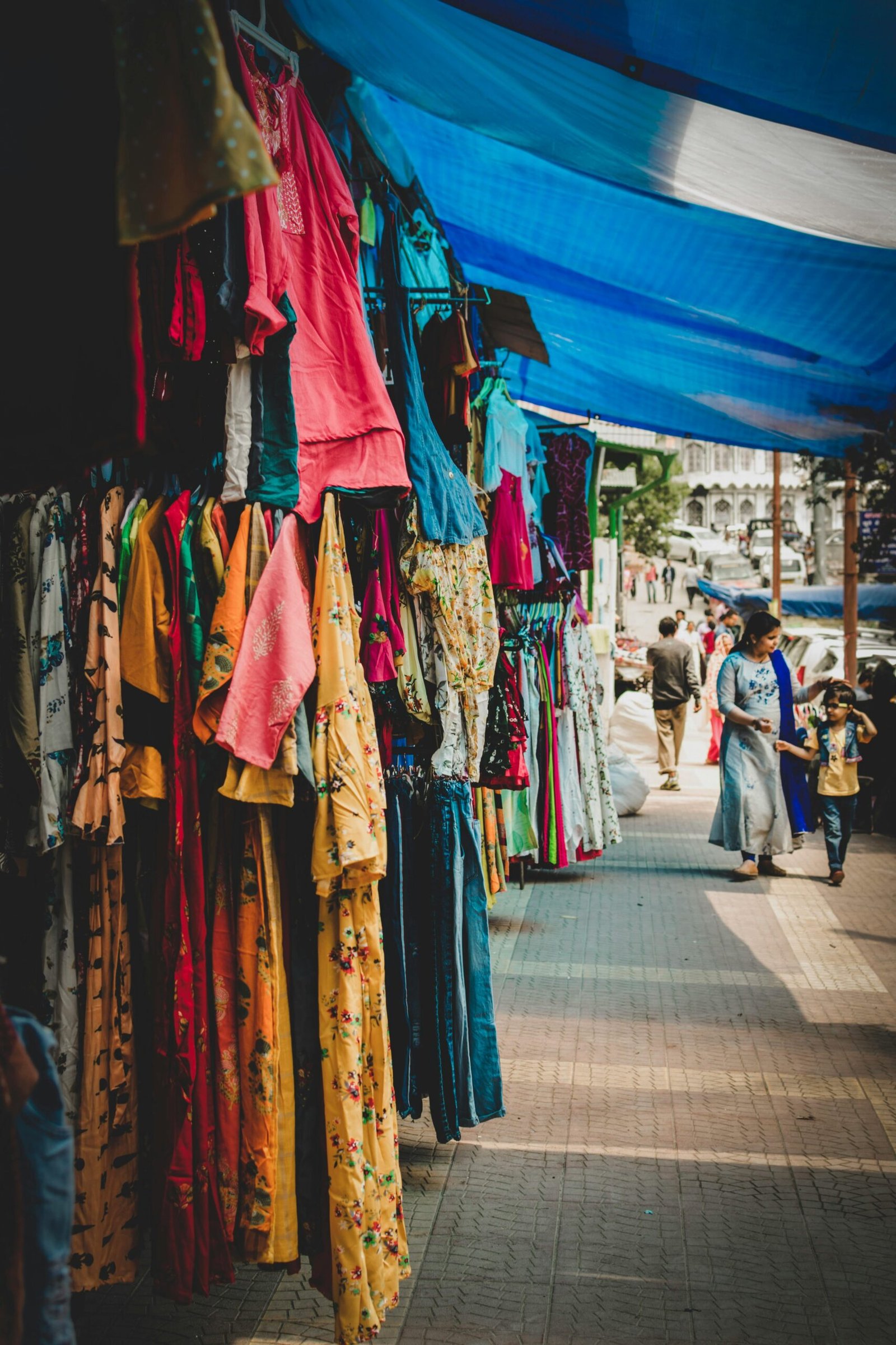 Colorful outdoor market showcasing hanging clothes and bustling street life.